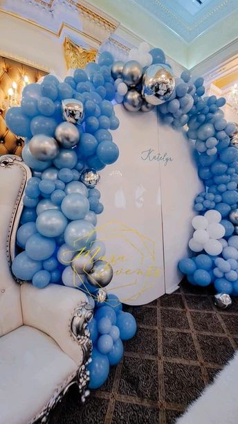 a balloon arch with blue and silver balloons in the shape of a wreath on top of a white chair