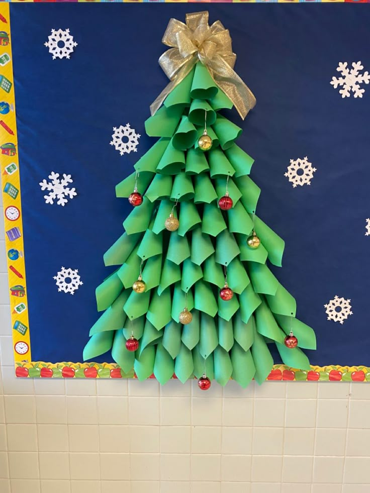 a christmas tree made out of green origami pieces on a blue and white wall