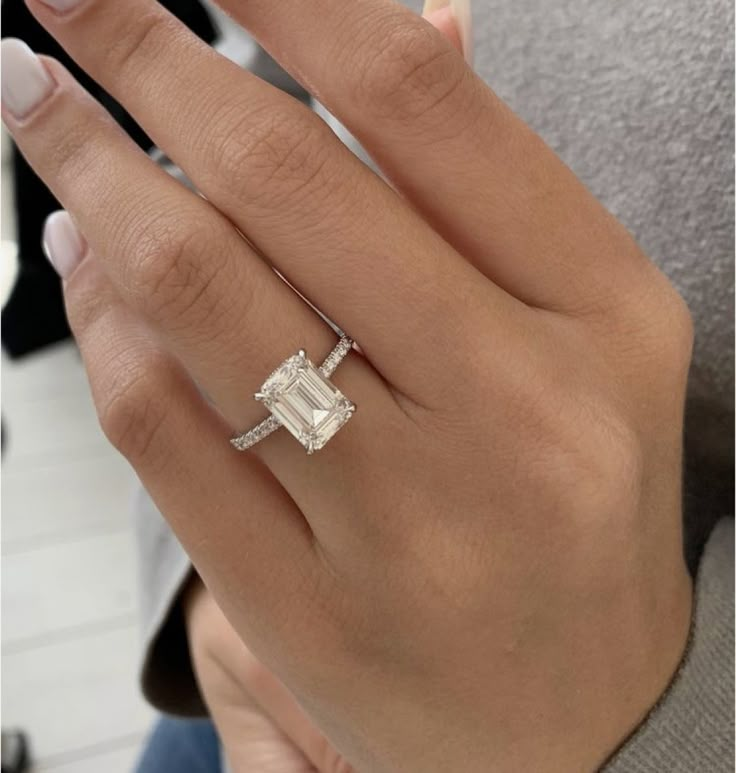 a woman's hand with an engagement ring and diamond band on her left hand