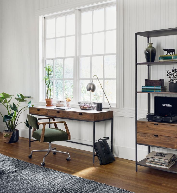 a room with a desk, chair and bookshelf next to a large window