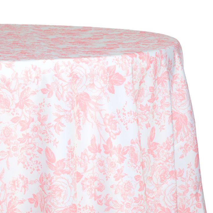 a pink and white table cloth with floral designs on the top, sitting on a round table