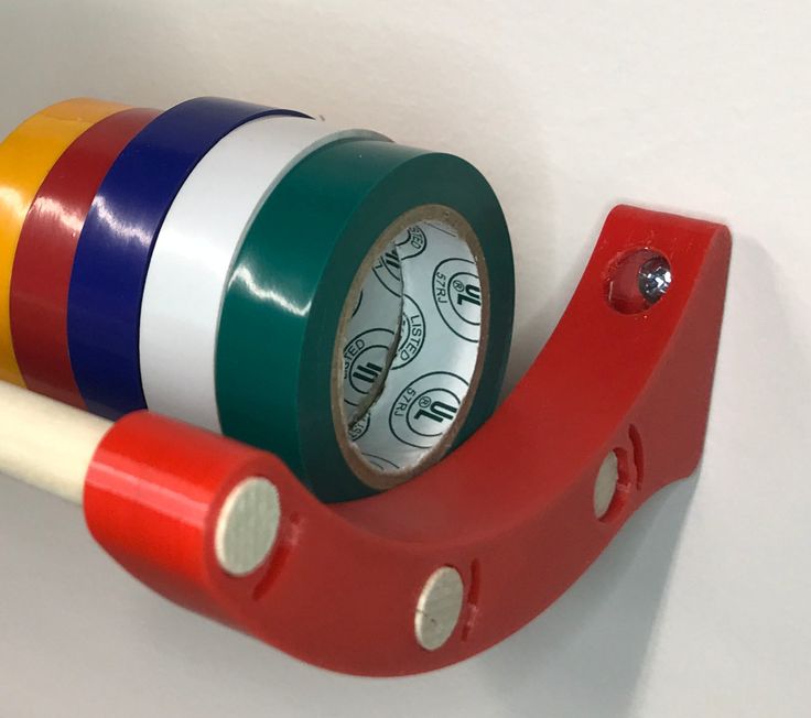 three rolls of colored tape are attached to a red holder with two white and one green