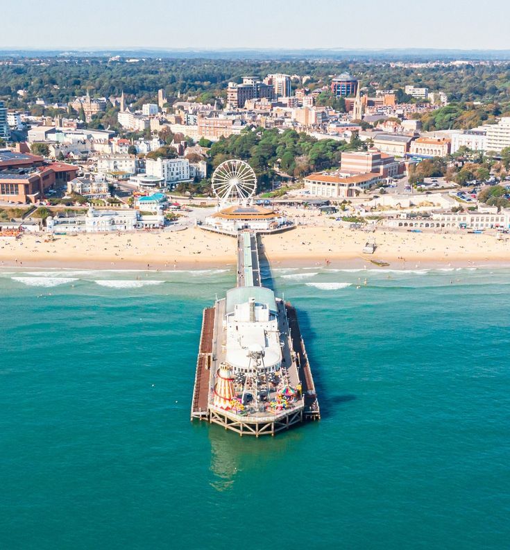 an aerial view of a pier in the middle of the ocean with a ferris wheel on top