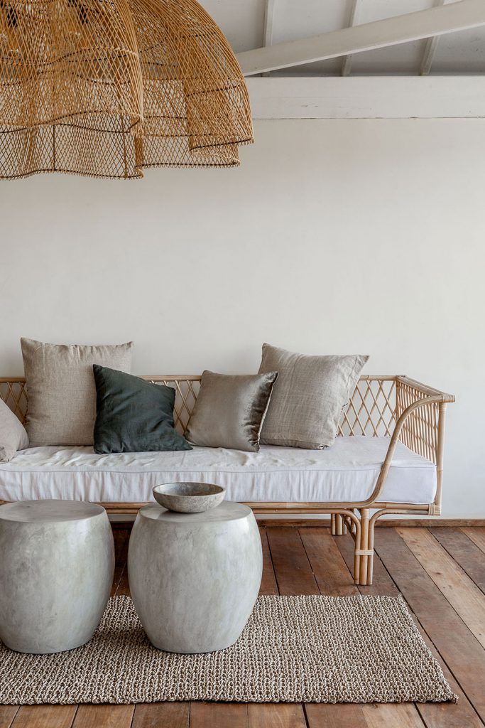 a white couch sitting on top of a wooden floor next to two round stools