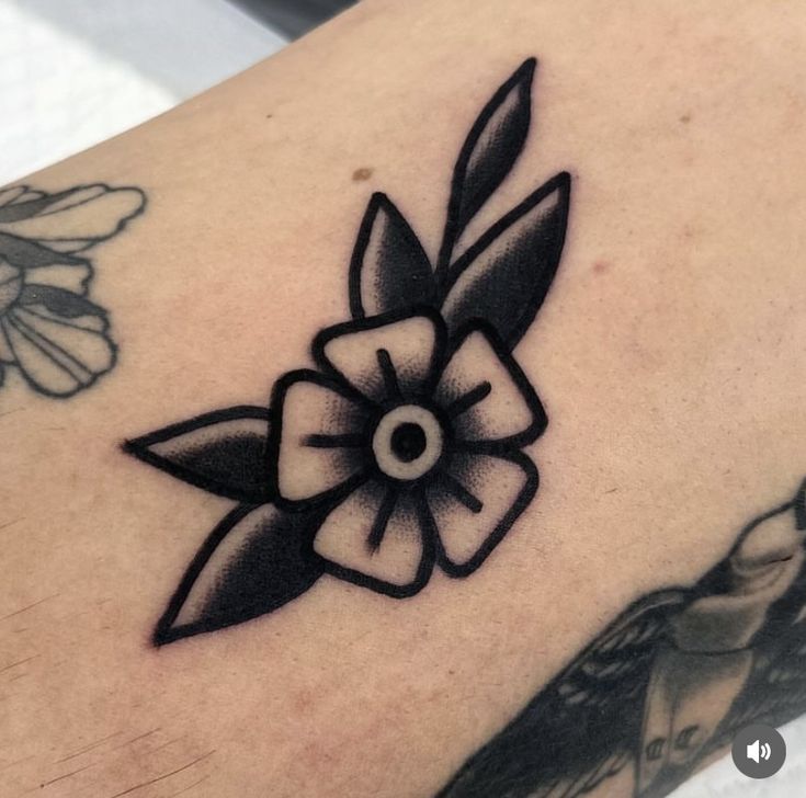 a black and white flower tattoo on the back of a woman's left arm