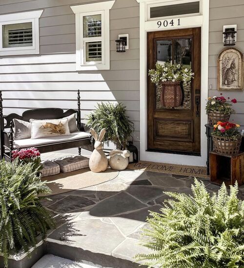 a front porch with potted plants and two benches