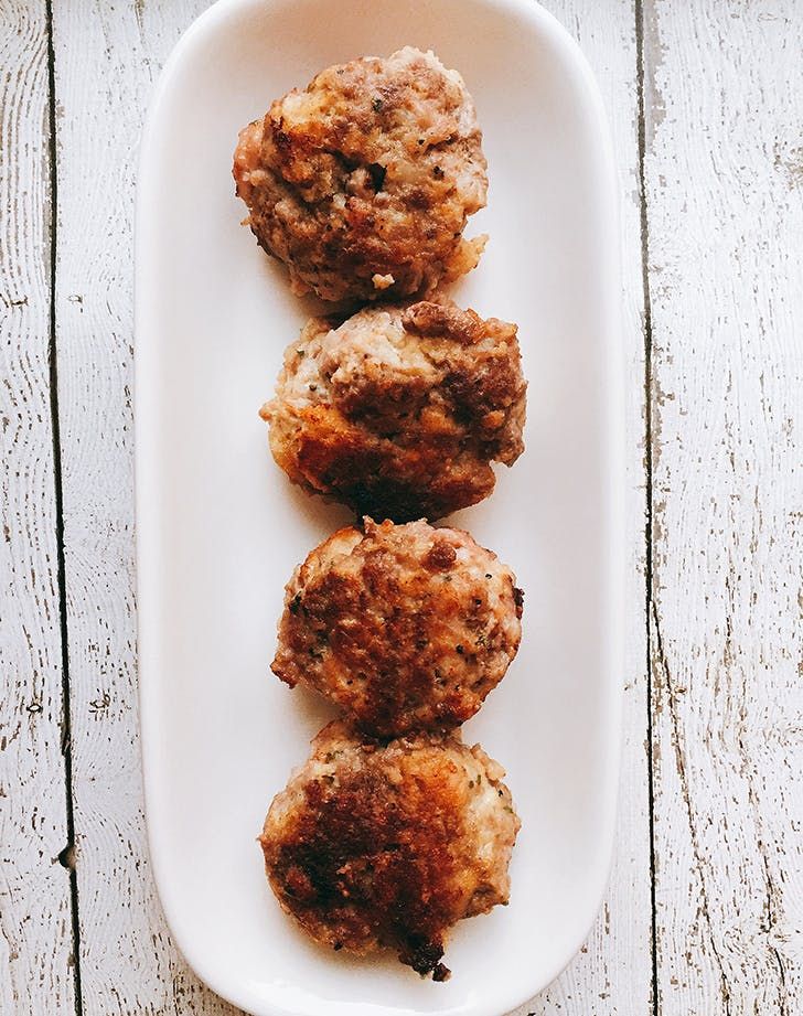 three meat patties on a white plate with a wooden table in the back ground