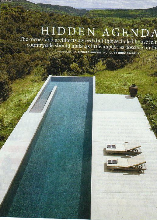 an aerial view of a swimming pool in the middle of a lush green hillside area