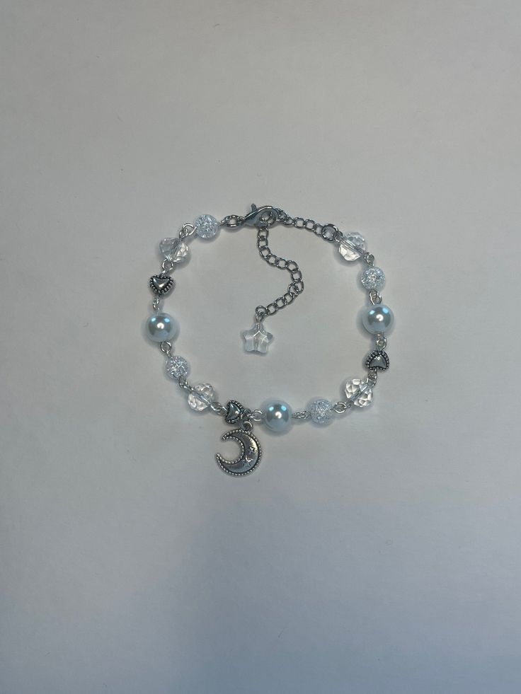 "Handmade silver beaded bracelet with silver moon and heart charms. Made with assorted clear, pearl and white cracked beads. Comes with 2.5inch extender making total length about 9.5\"." Moon Charm Bracelet, Silver Beaded Bracelets With Moon Charm As Gift, Silver Bracelets With Moon Charm And Round Beads, Silver Bracelet With Moon Charm And Round Beads, Silver Crystal Bracelet With Heart And Round Beads, Silver Crystal Bracelet With Heart Shaped Beads, Silver Metal Charm Bracelet With Pearl Charm, Silver Metal Bracelets With Moon Charm, Silver Metal Bracelet With Moon Charm