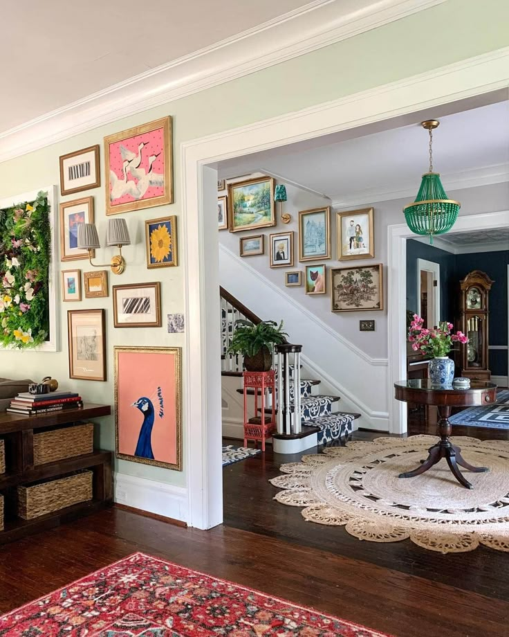 a living room filled with furniture and pictures on the wall next to a stair case