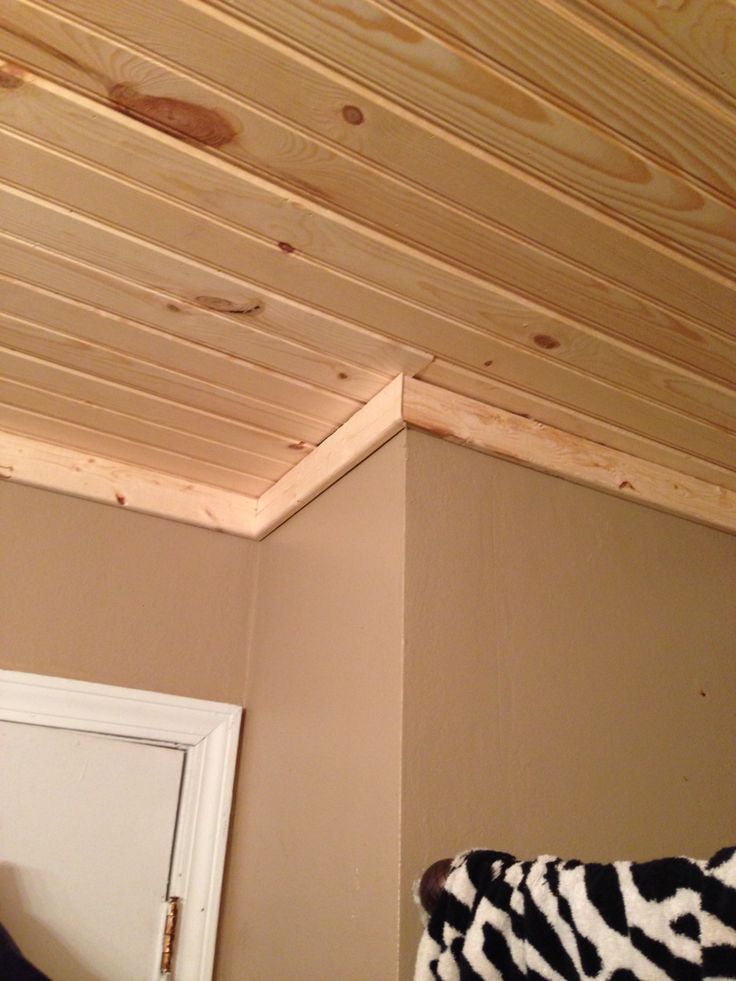 an unfinished ceiling with wood planks and a door in the corner next to it