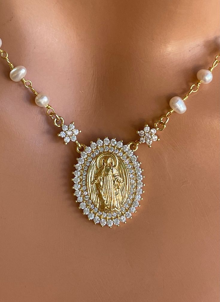 "This 14k gold-filled Virgin Mary pendant necklace with freshwater pearls approximately 3-3.5mm. Spring clasp on back. Mary pendant measures 20mm and has clear pave crystals. Model is wearing a 15\" length in photos. Necklace comes in many lengths, choose your length. Comes in a gift box ready to present!" Luxury Pearl Pendant Necklaces For Weddings, Luxury Bridal Necklace With Pearl Charm As Gift, Gold Royalty Necklace, Spiritual Jewelry The Catholic Company, Quinceanera Necklace Elegant, Luxury Crucifix Necklace For Formal Occasions, Luxury Crucifix Jewelry For Formal Occasions, Luxury Crystal Necklaces With Jewels As Gift, Luxury Fine Jewelry Cross Necklace As Gift