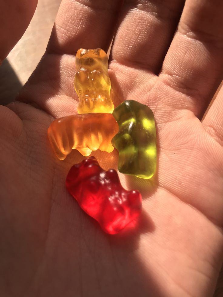 three gummy bears sitting on top of each other in someone's hand,