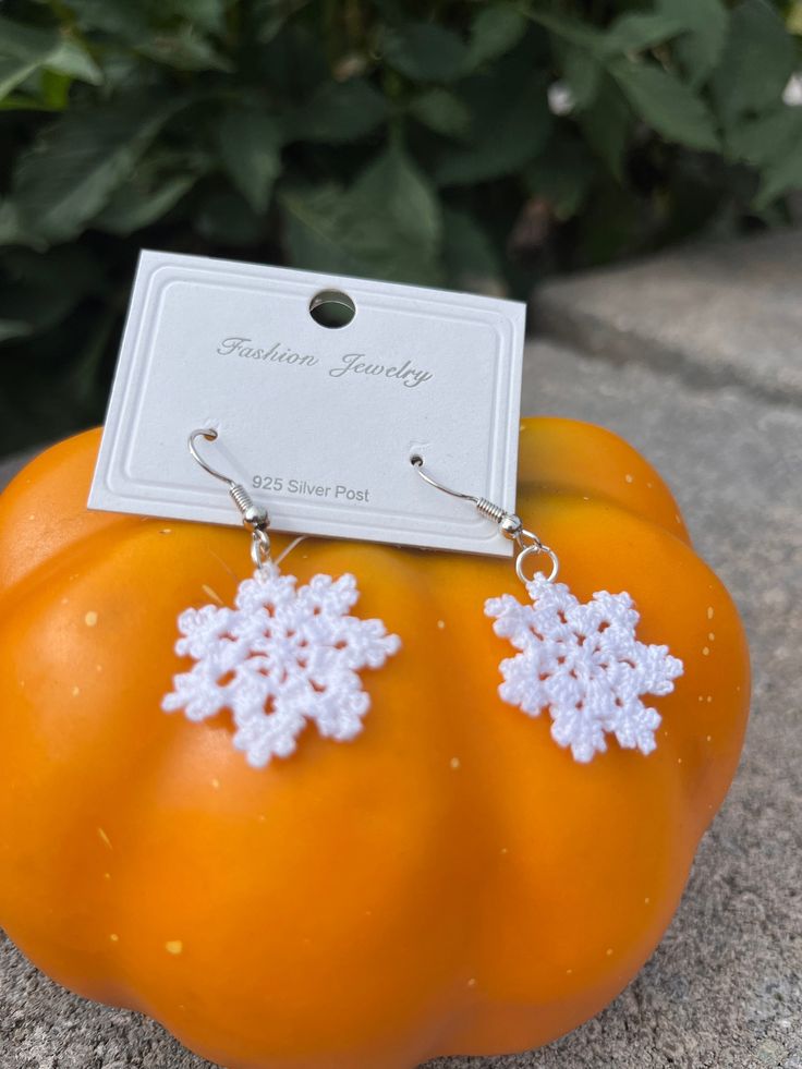 an orange pumpkin with snowflakes on it and a white tag hanging from the ear