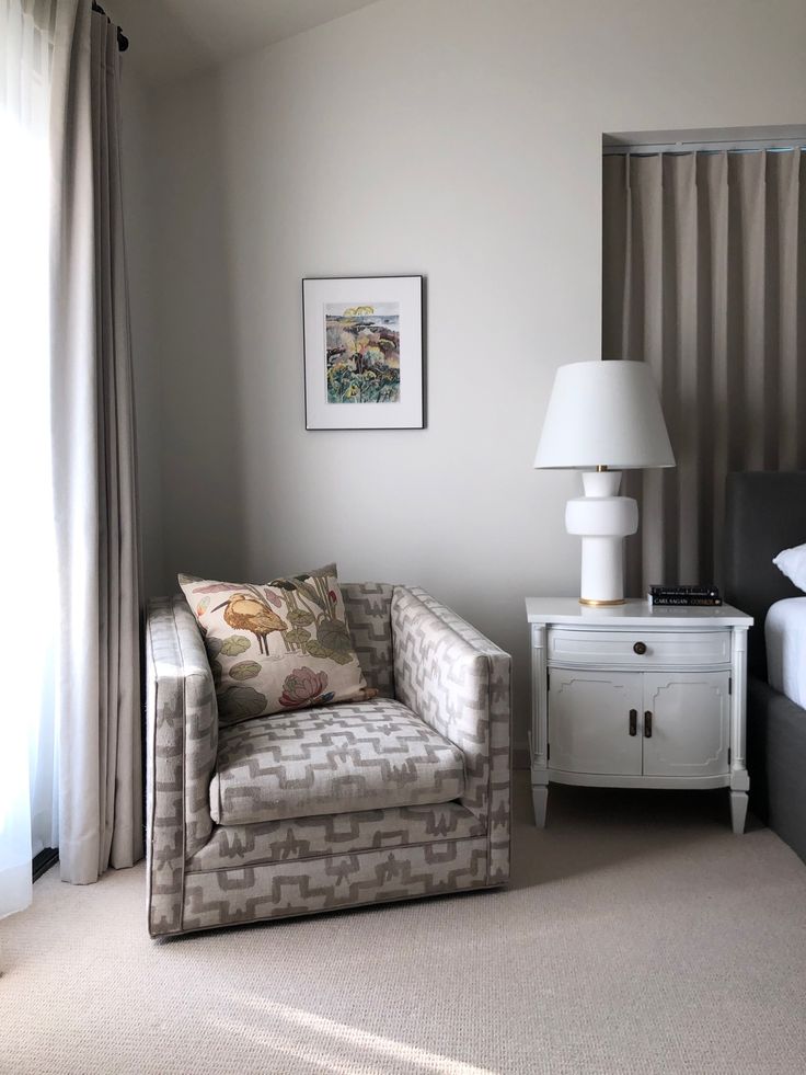 a bedroom with a chair, lamp and pictures on the wall