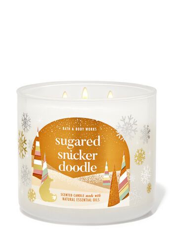 a candle that reads sugared snuggler doodle in front of snowflakes