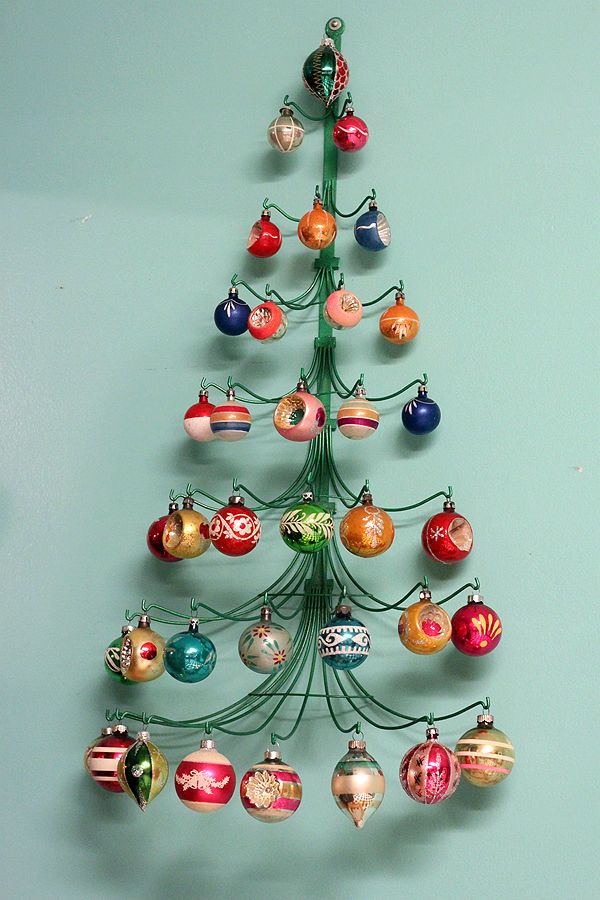 a small christmas tree with ornaments hanging from it's sides on a blue wall