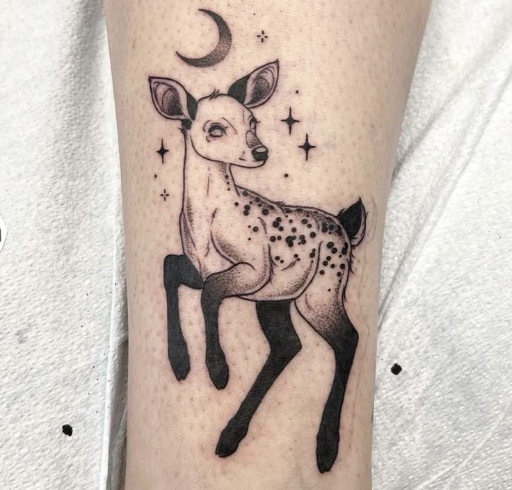 a small deer tattoo on the right leg with stars and moon in it's head