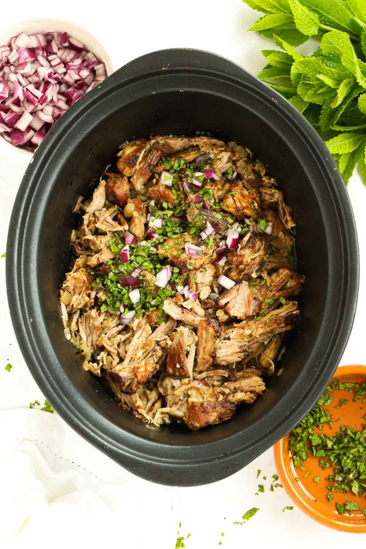 a bowl filled with meat, onions and herbs