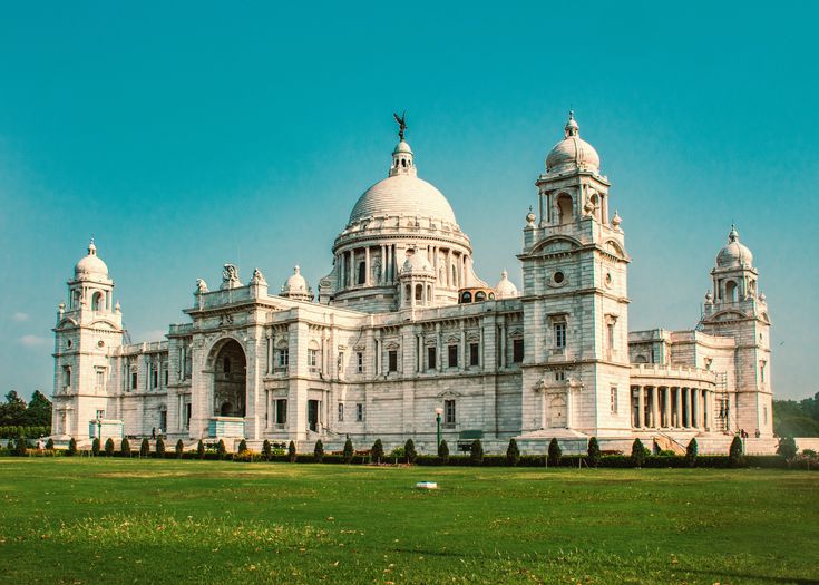 a large white building sitting on top of a lush green field