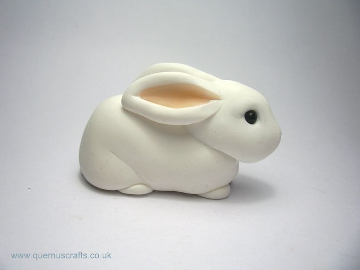 a white ceramic rabbit sitting on top of a table next to a cup filled with liquid