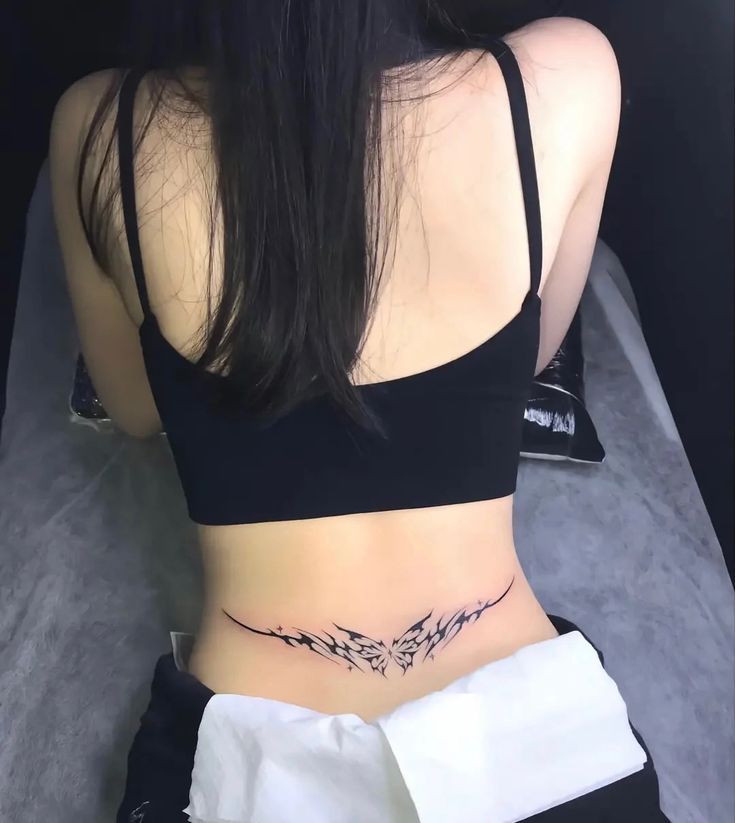 the back of a woman's stomach with an arrow tattoo on her left side