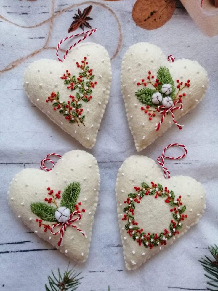 four white heart ornaments with holly and berries on them