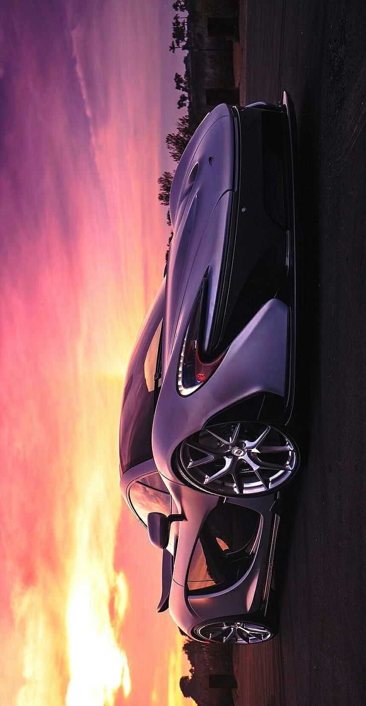 a car parked on the side of a road next to a fire hydrant in front of a sunset