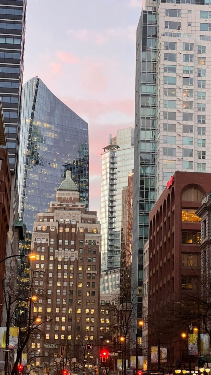 a city street filled with lots of tall buildings next to traffic lights and trees in the foreground