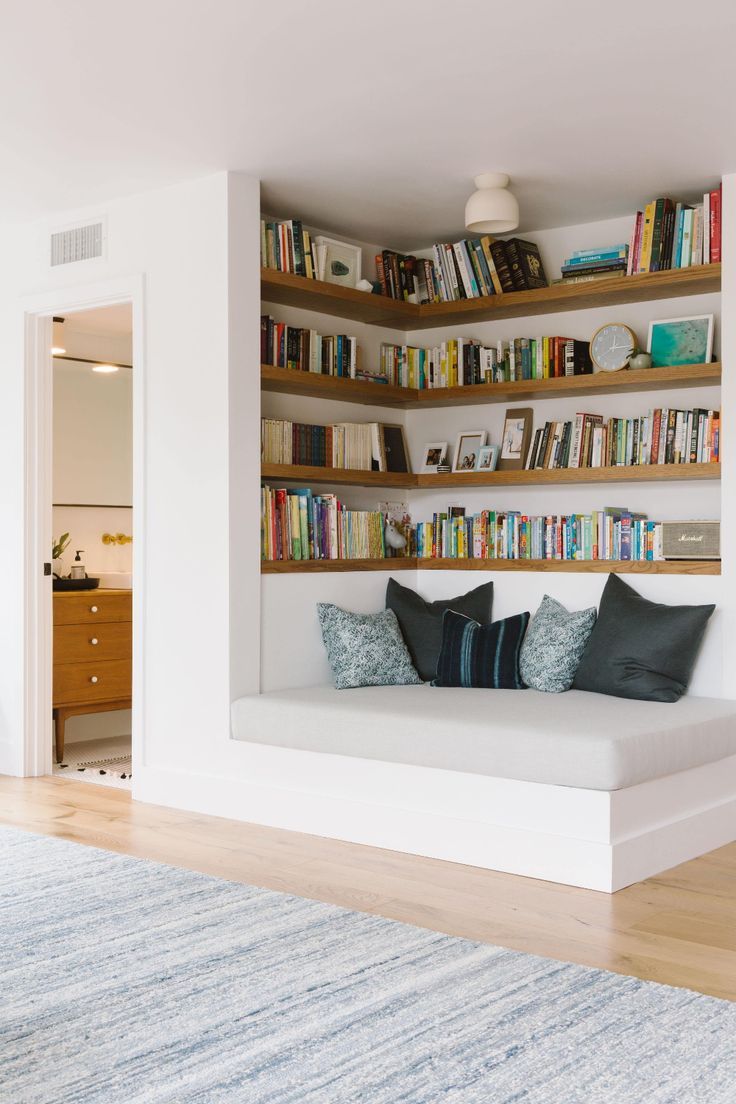 a living room filled with furniture and bookshelves next to a doorway that leads to a bedroom