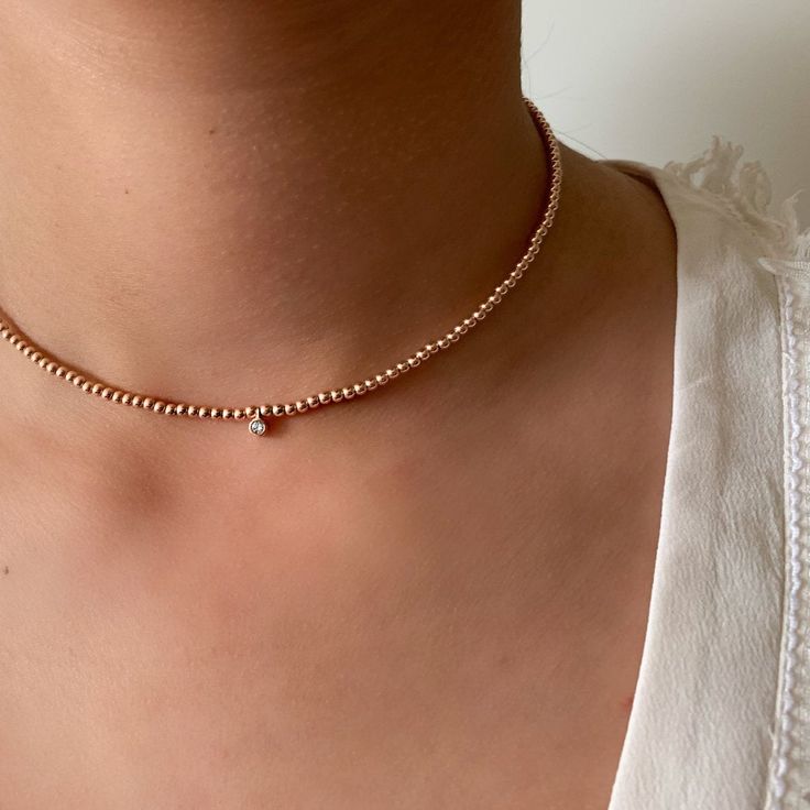 Our 14k solid gold beaded choker necklace features 2.5mm medium weight seamless round beads with a 0.05ctw diamond dangle charm also in 14k. The necklace is adjustable with a 2 inch extension chain. You can purchase this necklace is solid 14k gold ( hallmarked with 585/14k gold) with 14k gold beads and 14k gold 0.05ctw diamond charm or you can opt for the more economical version which features gold filled beads with a 14k solid gold diamond 0.05ctw charm ( charm is hallmarked 585/14k gold) Detai Rose Gold Jewelry With Tiny Beads, Dainty Diamond Jewelry With Satellite Chain, Single Strand Diamond Bead Jewelry, Rose Gold Necklaces With Round Tiny Beads, Dainty Single Strand Diamond Jewelry, Dainty Rose Gold Beaded Necklace With Round Beads, Dainty Beaded Rose Gold Jewelry, Dainty Rose Gold Beaded Necklaces, Dainty Rose Gold Jewelry With Tiny Beads