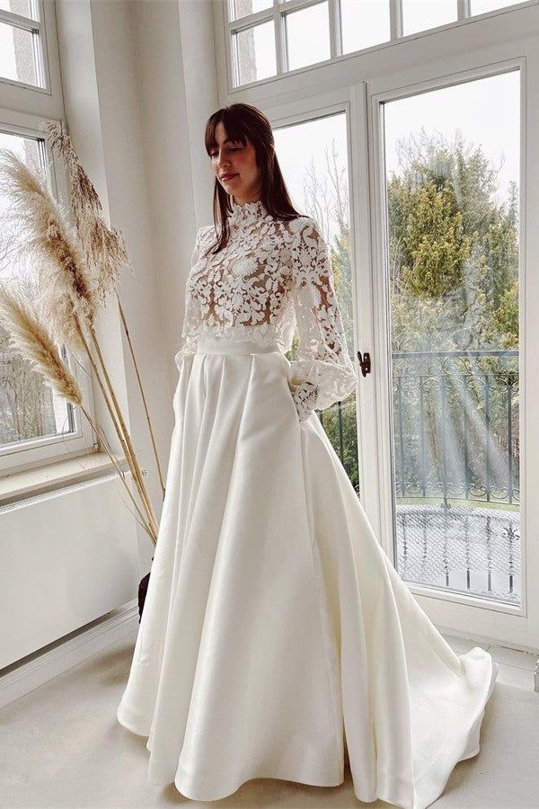 a woman in a white wedding dress standing next to a window with tall pamodia