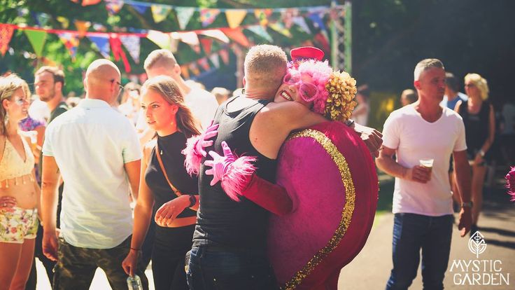 two people hugging each other in front of a group of people on the street with flags and bunting