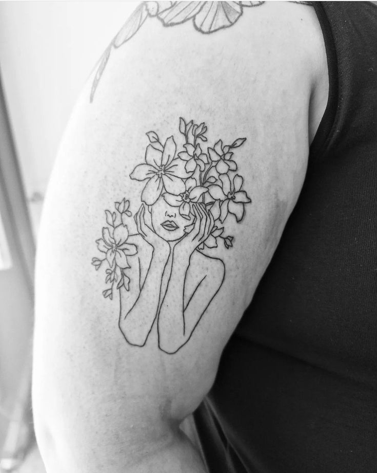 a woman with flowers in her hair is wearing a black and white tattoo on her arm