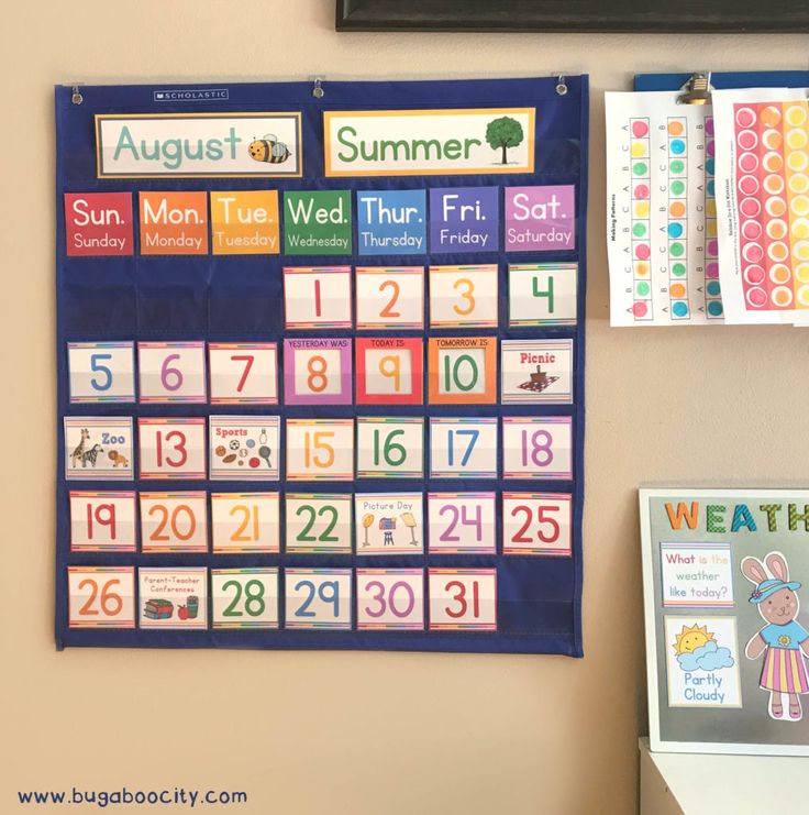 a bulletin board with colorful calendars on it next to a wall clock and magnets