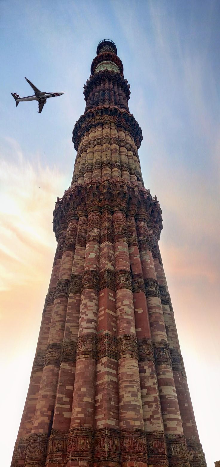 an airplane flying in the sky over a tall tower