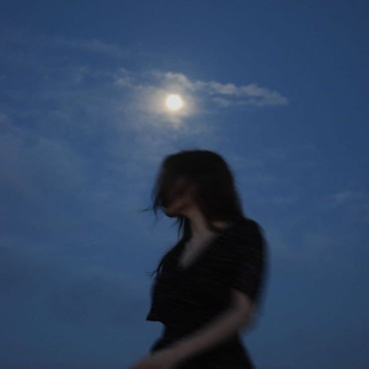 a woman is walking in the moonlight with her hand on her hip