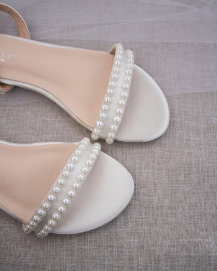 Classy satin flat sandals with a mini pearls and ankle strap. Effortless yet adorable to wear on your favorite occasion. Can be pair with dress or casual look.DETAILS:COLORS AVAILABLE: IvoryUPPER: Synthetic upper and liningMATERIALS: Mandmade outsoleSTYLE NAME: MADDY Flat Summer Wedding Shoes For Bridesmaids, Bridal Shower Pearl Embellished Ankle Strap Sandals, Elegant White Beaded Sandals, Spring Wedding Beaded Sandals, Beaded Open Toe Sandals For Wedding, White Beaded Sandals For Wedding, White Beaded Wedding Sandals, Elegant Beaded Flat Sandals, Summer Open Toe Pearl Wedding Shoes