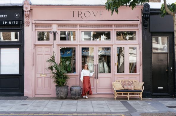 a woman standing in front of a pink store