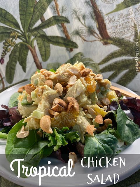 a white plate topped with salad next to a green leafy plant covered wallpaper