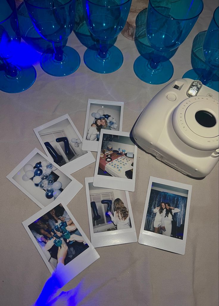 several polaroid pictures and a camera on a table with blue glass vases in the background