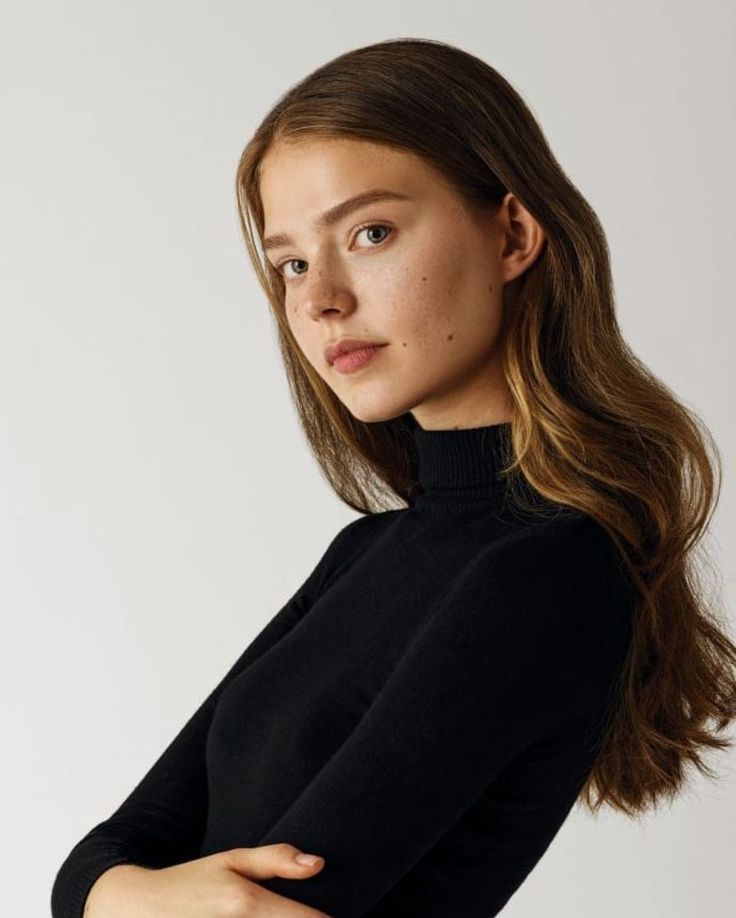 a woman with her arms crossed posing for the camera, wearing a black turtle neck sweater