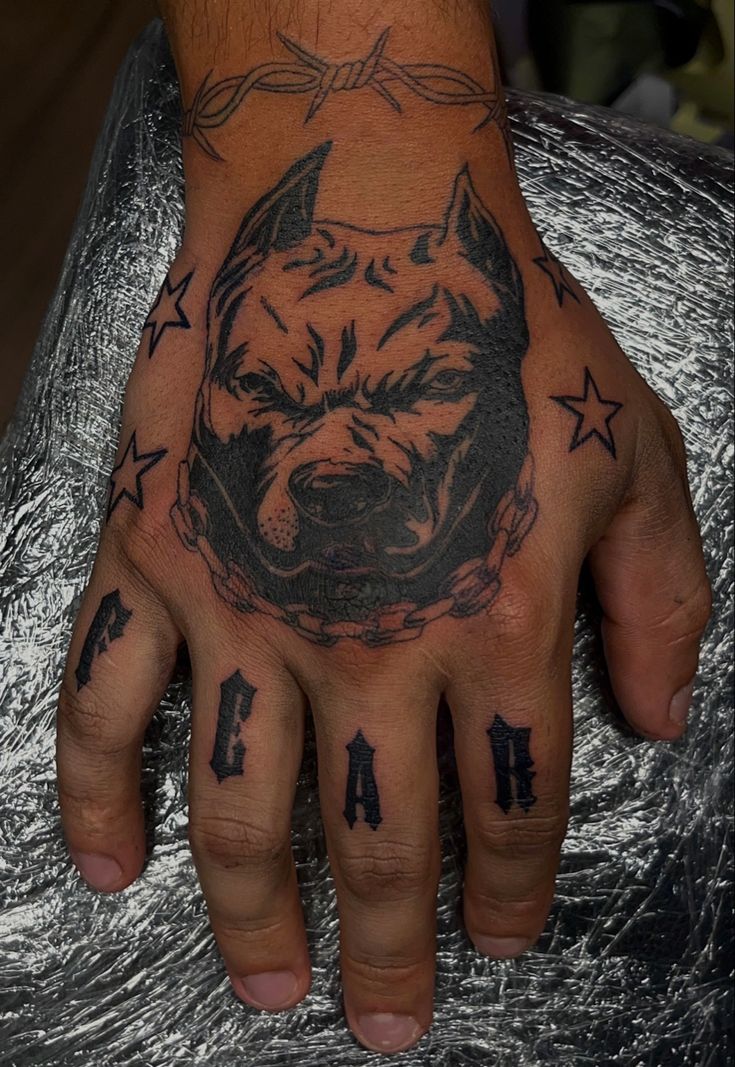 a man's hand with tattoos on it and a pitbull in the middle