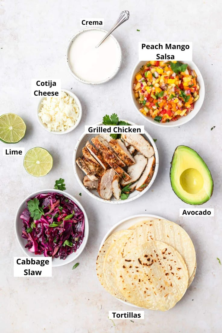 the ingredients to make chicken fajita laid out on a white surface with limes