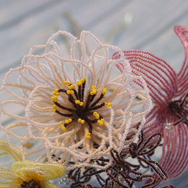 three different colored flowers sitting on top of a wooden table