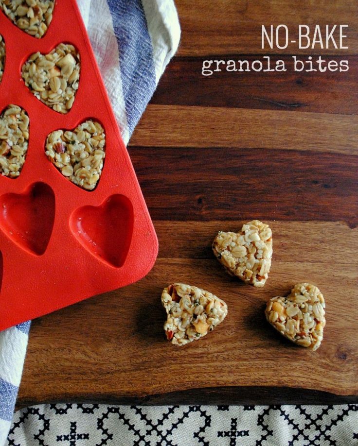 no bake granola bites in the shape of hearts on a wooden cutting board