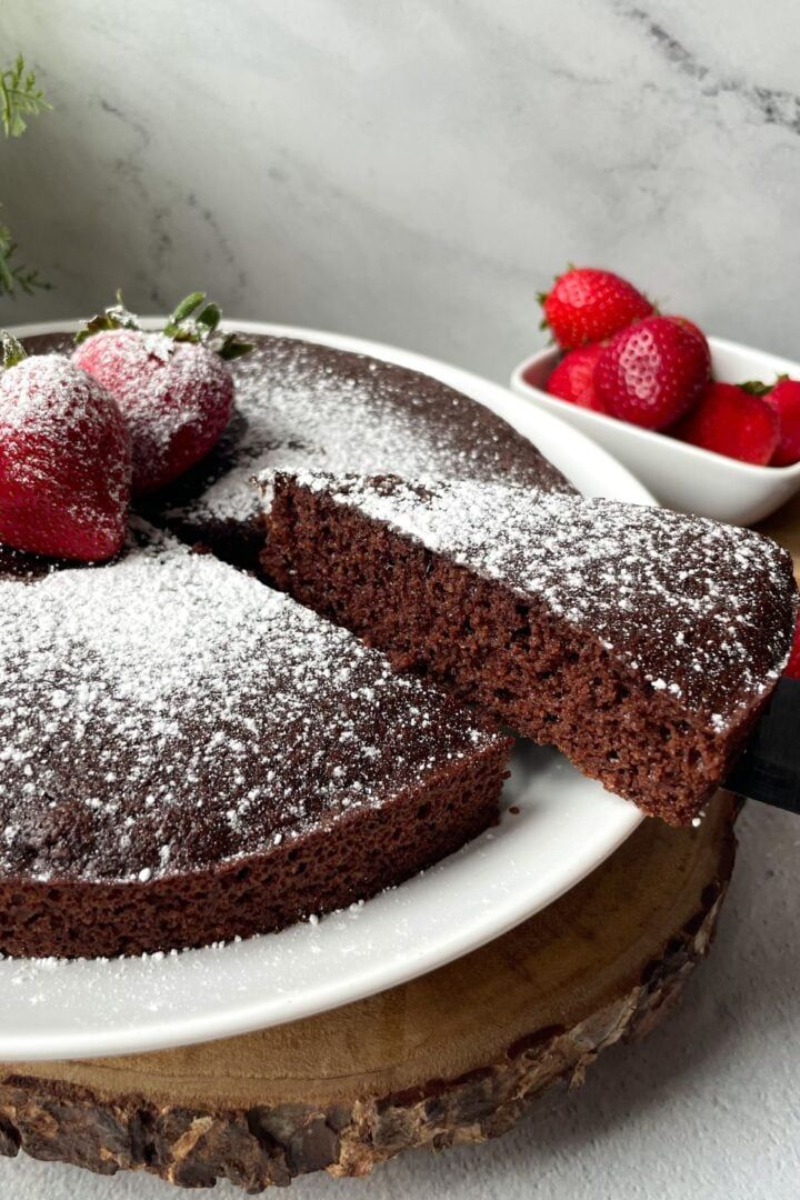 a chocolate cake with powdered sugar and strawberries on the plate next to it