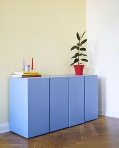 a blue cabinet sitting on top of a wooden floor next to a potted plant