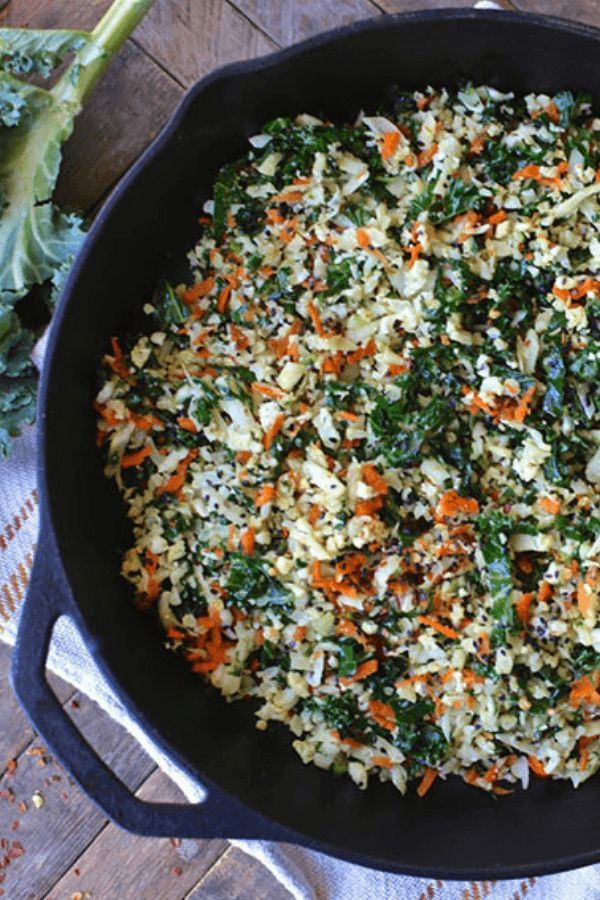 a skillet filled with vegetables on top of a wooden table next to broccoli