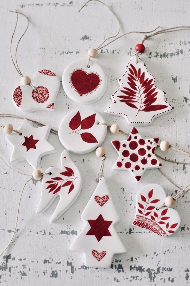 christmas ornaments are hanging on a white table with red and white decorations in the shape of trees